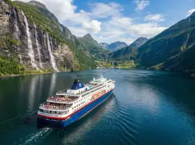 Rejs statkiem "Norwegian Fjord Explorer" przez malownicze fiordy Norwegii, z wodospadami i zielonymi zboczami.