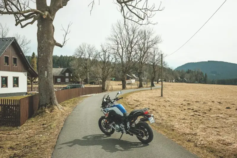 Motocykl czeka na jednodniowy wypad motocyklowy. W tle wiejskie domki i puste pola.